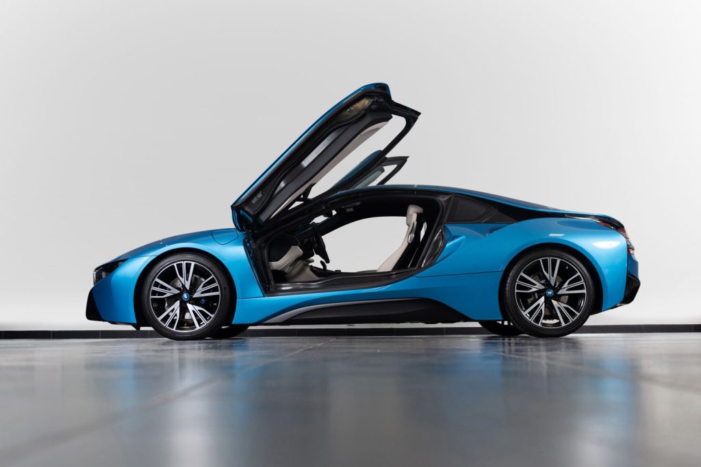 BMW i8 med öppna fjärilsdörrar, fotograferad i en stilren studiomiljö.