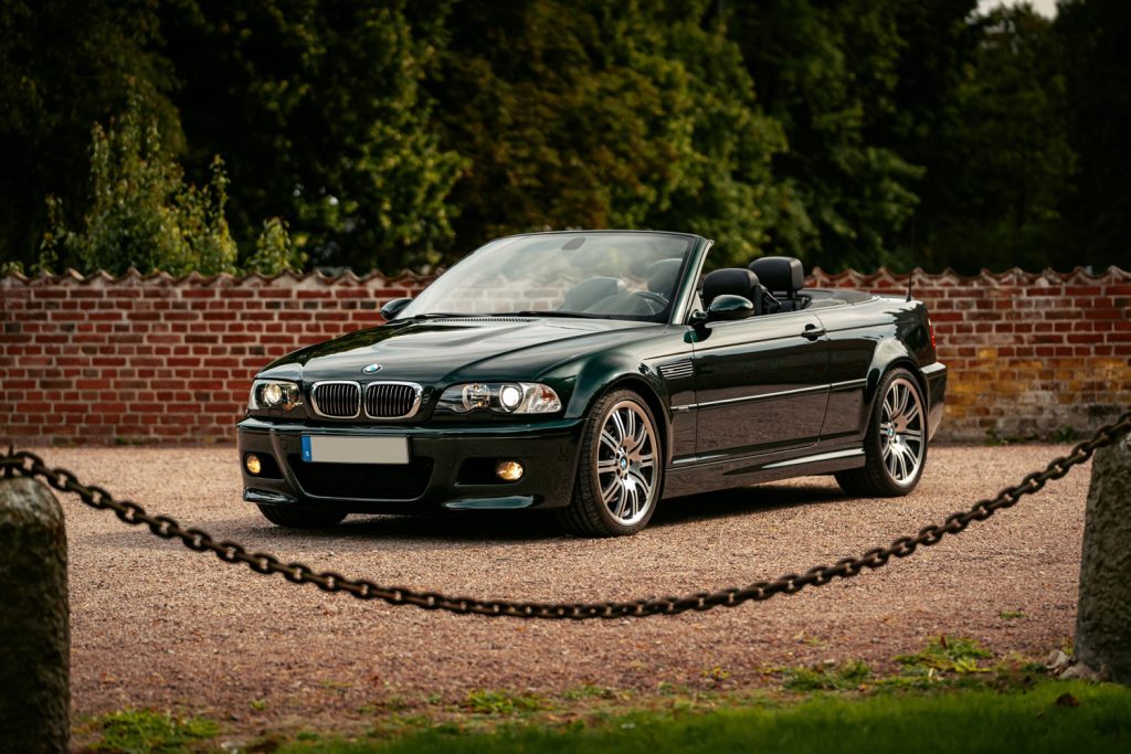 BMW M3 Cabriolet parkerad framför en grönskande bakgrund, fotograferad på en stenlagd väg.