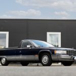 Cadillac Flower Car i midnattsblå metalliclack med kromdetaljer, fotograferad utomhus vid modern byggnad av Runbox Sweden.