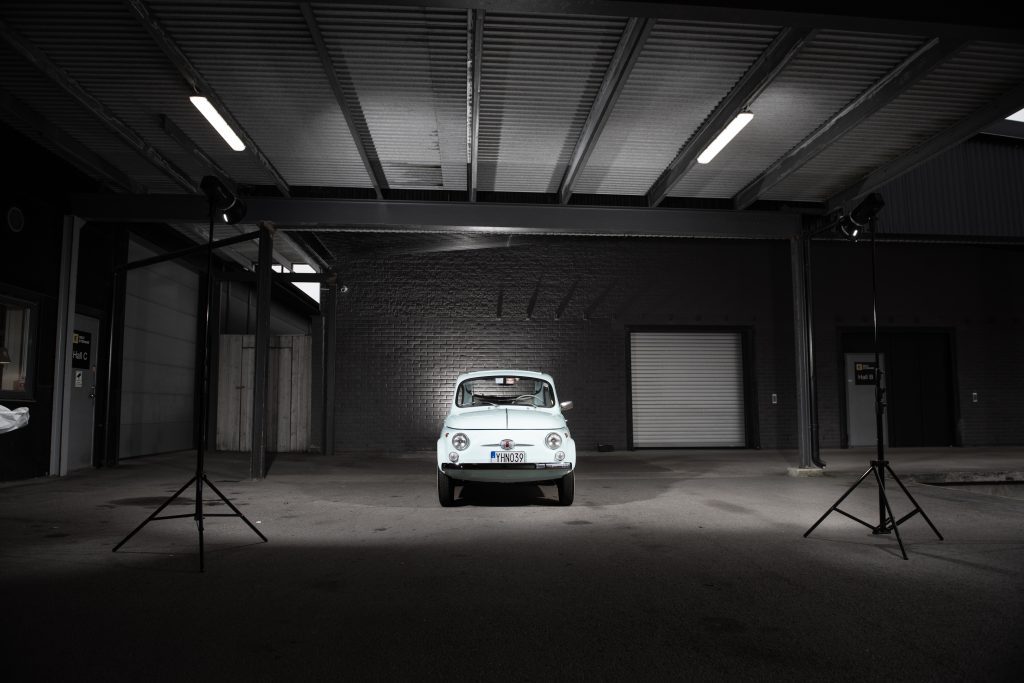 Fiat 500 fotograferad framifrån i ett professionellt upplyst garage, perfekt för bilförsäljning och auktion.