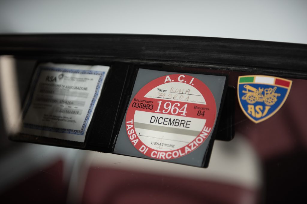 Närbild på detalj i Fiat 500, visar ett klassiskt emblem på rutan.