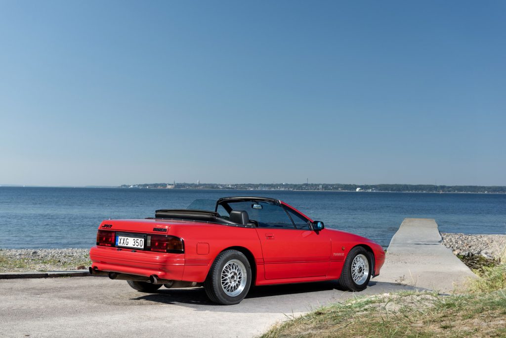 Mazda RX7 i Helsingborg med en vacker havsbakgrund, professionell fotografering och Wankelmotor.