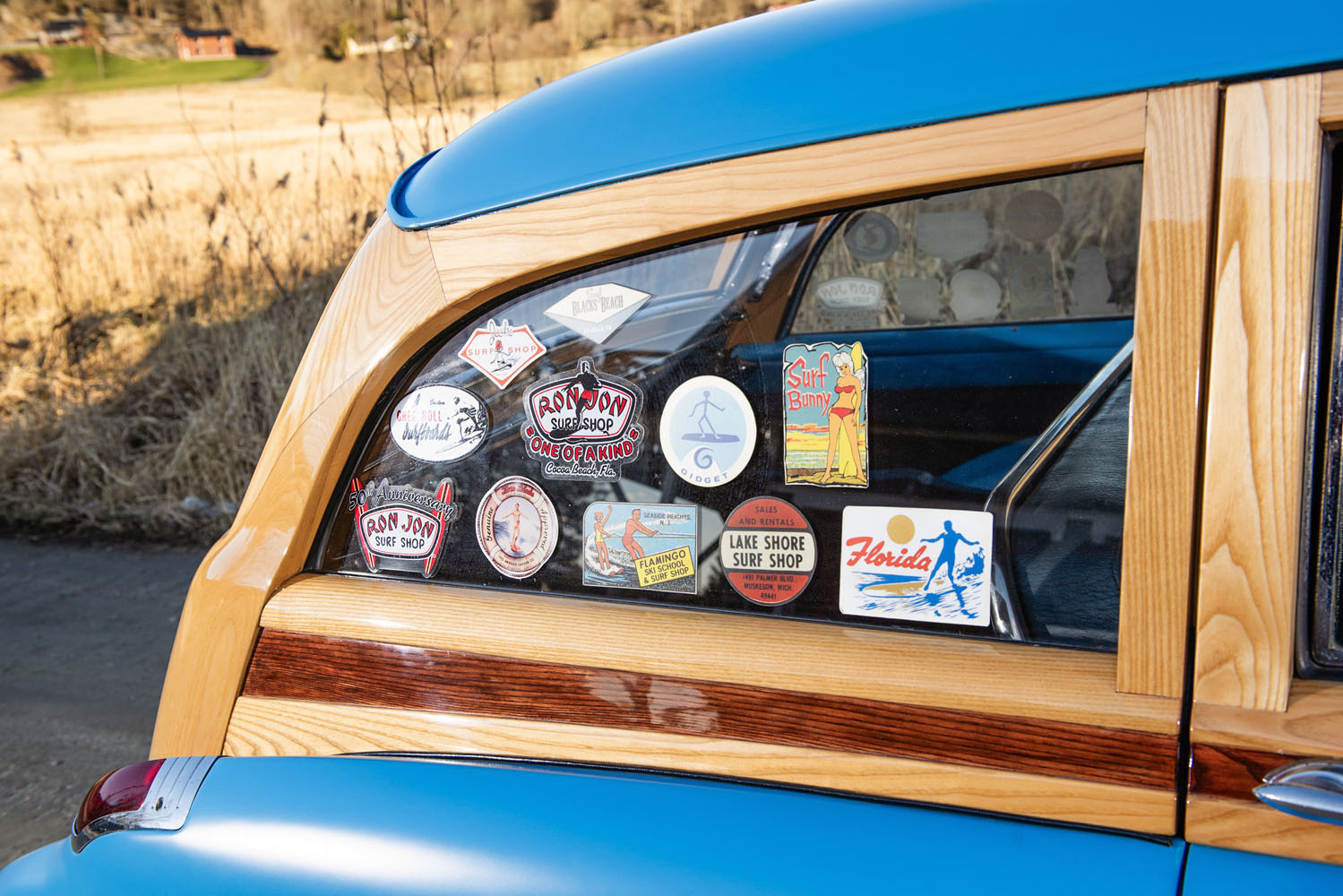 Klistermärken från amerikanska surfbutiker på bakrutan av en 1950 Buick Super Woody – redo för export till USA.