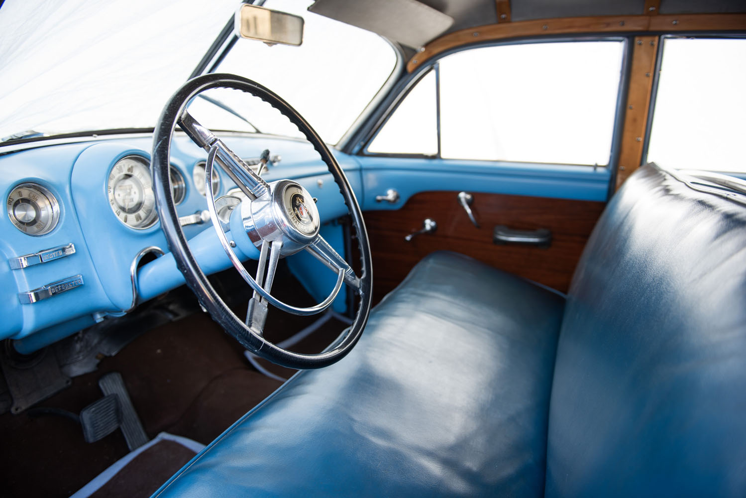 Interiör av 1950 Buick Super Woody – blå ratt, bänksäte och klassisk amerikansk trädetalj från bilens guldålder.