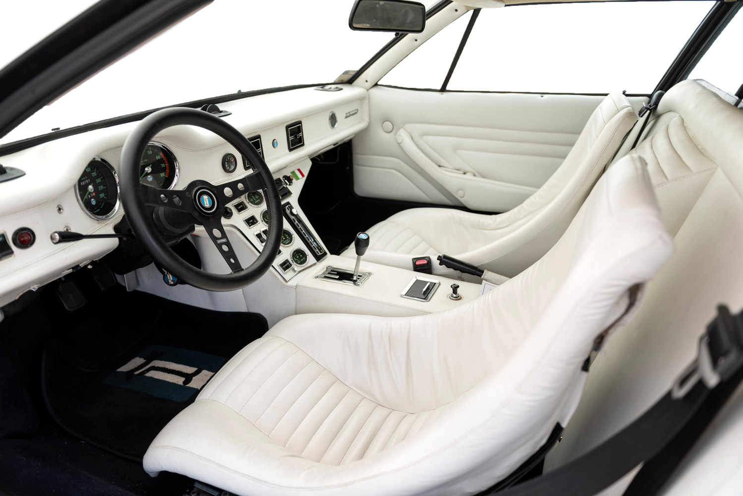 Interiör i De Tomaso Pantera GTS – vit läderinredning och italiensk instrumentpanel med gröna mätare.