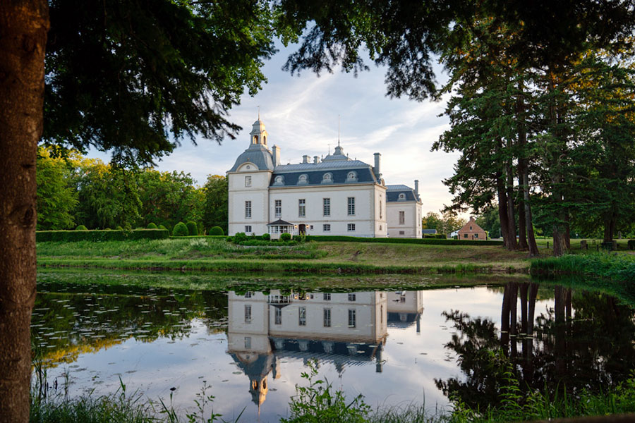 Kronovalls slott på Österlen speglas i vallgraven.